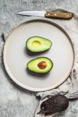 Olgun avokado yarım kilden bir tabakta. Gri arka plan. Üst görünüm