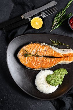 Pirinç ve ıspanakla süslenmiş ızgara biftek. Sağlıklı deniz ürünleri. Siyah arka plan. Üst görünüm