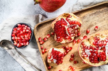 Tahta bir kasede taze, olgun bir nar. Organik meyve. Gri arka plan. Üst görünüm