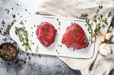 Mermer sığır filetosu. Beyaz kesim tahtasında çiğ fileminyon biftek. Gri arka plan. Üst görünüm