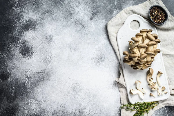 Färska ostronsvampar på en vit hackbräda med timjan. Grå bakgrund. Högst upp. Plats för text — Stockfoto