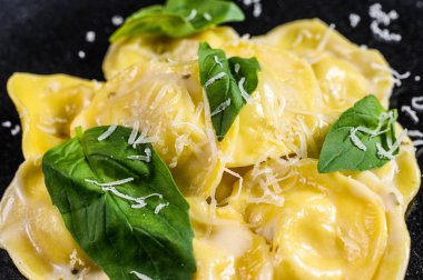 Bir tabak parmesanlı ravioli ve fesleğen. Siyah arka plan. Üst görünüm