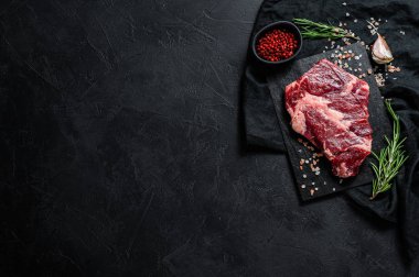 Doğrama tahtasında çiğ biftek. Organik çiftlik eti. Siyah arka plan. Metin için boşluk