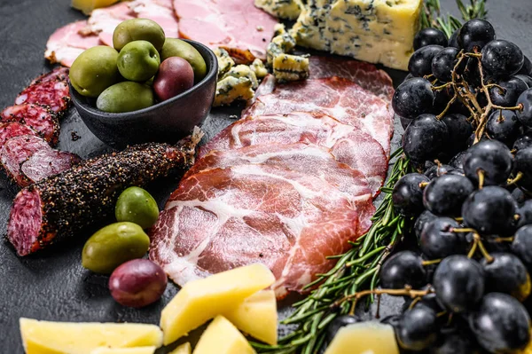 Antipasto tipico italiano con prosciutto, prosciutto, formaggio e olive. Fondo nero. Vista dall'alto — Foto Stock