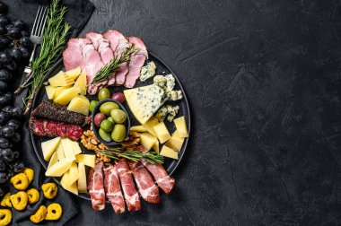 Prosciutto, jambon, peynir ve zeytinli tipik İtalyan antipasto. Siyah arka plan. Üst Manzara. Metin için boşluk