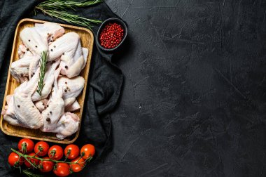 Tahta bir kasede çiğ tavuk kanadı. Çiftlik organik eti. Üst Manzara. Siyah arka plan. Metin için boşluk.