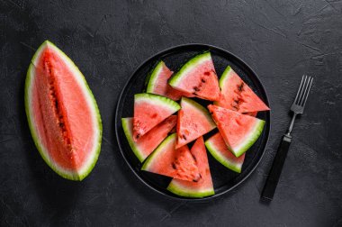 Olgun karpuz dilimleri koyu arkaplanda bir tabakta. Seçici odak.