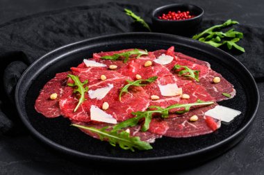 Arugula ve parmesan peynirli mermer sığır carpaccio. Siyah arka plan. Üst görünüm