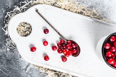 Demir bir kupada olgun kırmızı kızılcıklar. Gri arka plan. Üst görünüm