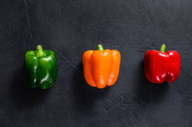 Yeşil, turuncu ve kırmızı dolma biber. Siyah arka plan. Üst Manzara. Metin için boşluk.
