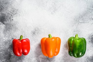 Yeşil, turuncu ve kırmızı dolma biber. Gri arka plan. Üst Manzara. Metin için boşluk.