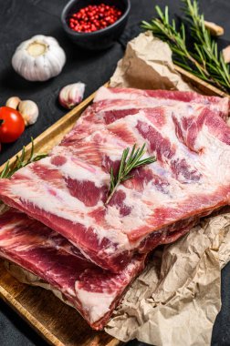 Biberiye ve ahşap bir kasede sarımsak pişirmek için malzemeli çiğ domuz eti pirzolası. Siyah arka plan. Üst görünüm