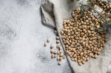 Kurutulmuş nohutlar cam bir kavanozdan döküldü. Sağlıklı vejetaryen yemekleri. Gri arka plan. Üst Manzara. Metin için boşluk
