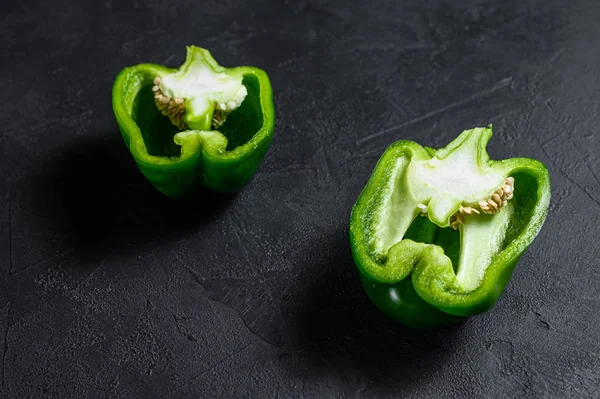 Klipp grön paprika, två halvor. Svart bakgrund. Ovanifrån. — Stockfoto
