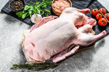 Tamamen çiğ kaz. Pembe tuz, sarımsak, maydanoz ve biberiyeli yemek tarifi. Gri arka plan. Üst görünüm