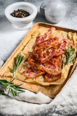 Ahşap doğrama tahtasında kızarmış pastırma. Biberiye ve karabiberle servis et. Gri arka plan. Üst görünüm