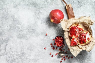 Olgun nar ve tahtadan bir kesme tahtasındaki tohumlar. Organik meyve. Gri arka plan. Üst Manzara. Metin için boşluk