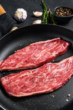 Kızartma tavasında çiğ mermer biftek. Siyah arka plan. Üst görünüm