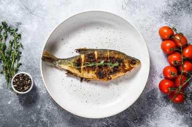 Beyaz tabakta ızgara sazan balığı. Nehir organik balığı. Gri arka plan. Üst görünüm