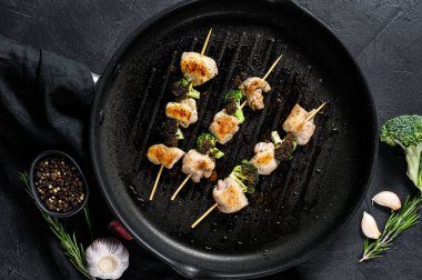 Izgara tavuk göğsü şişleri. Brokoli. Siyah arka plan. Üst görünüm