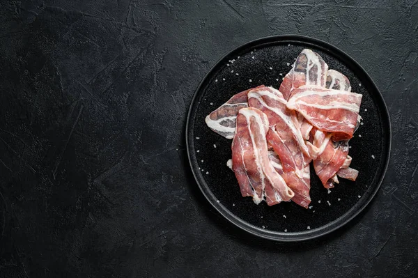 Pork bacon on a black plate. Farm organic meat. Black background. Top view. Space for text — Stock Photo, Image