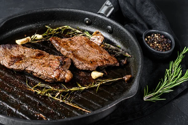 Rump steak en una sartén. Carne a la parrilla. Fondo negro. Vista superior —  Fotos de Stock