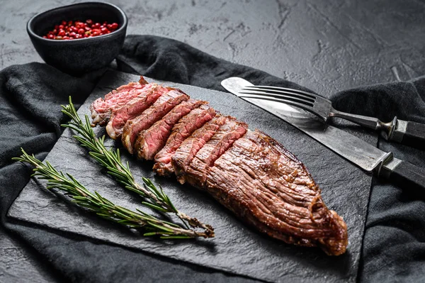 Márványmarhahúsos steak, közepesen átsütve egy fekete kőtáblán. Fekete háttér. Felülnézet — Stock Fotó