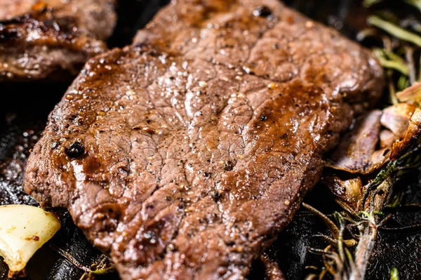 Filete de lomo en una sartén. Carne a la parrilla. Fondo negro. Vista superior — Foto de Stock