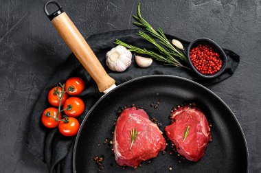 Kızartma tavasında çiğ fileminyon biftek. Sığır filetosu. Siyah arka plan. Üst görünüm