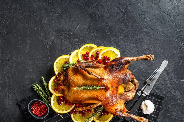 Gebackene Ente gefüllt mit Orangen und Rosmarin. Festtafel. Schwarzer Hintergrund. Ansicht von oben. Raum für Text — Stockfoto