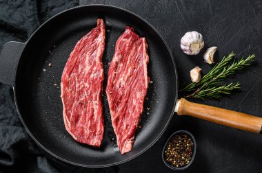 Kızartma tavasında çiğ mermer biftek. Siyah arka plan. Üst görünüm