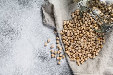 Kurutulmuş nohutlar cam bir kavanozdan döküldü. Sağlıklı vejetaryen yemekleri. Gri arka plan. Üst Manzara. Metin için boşluk