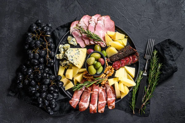 Antipasto bordo com carne fatiada, presunto, salame, queijo, azeitonas. Fundo preto. Vista superior — Fotografia de Stock