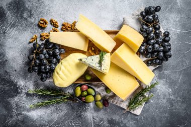 Üzüm, kraker, zeytin ve fındık ile servis edilen peynir tabağı. Çeşit çeşit lezzetli atıştırmalıklar. Gri arka plan. Üst görünüm