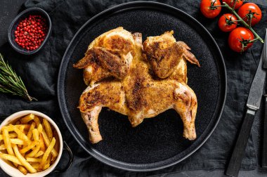 Siyah tabakta servis edilen biberiyeli kızarmış tavuk. Siyah arka plan. Üst görünüm