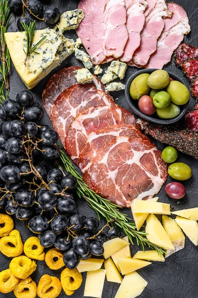 Antipasto tallrik med skinka, prosciutto, salami, blåmögelost, mozzarella och oliver. Svart bakgrund. Ovanifrån — Stockfoto