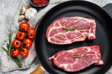 Kızartma tavasında çiğ biftek. Mermer çiftlik eti. Gri arka plan. Üst görünüm