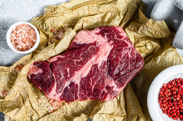 Raw marbled beef steak on a chopping Board. Organic farm meat black Angus. Gray background