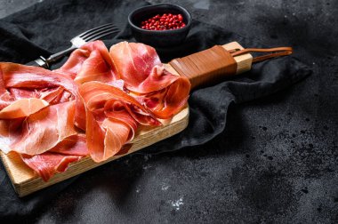 Prosciutto Crudo, İtalyan salamı, parma jambonu. Antipasto tabağı. Siyah arkaplan, üst görünüm, metin için boşluk