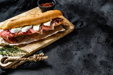 Jambonlu sandviç, dilimleme tahtasındaki peynirli peynirli sandviç. Siyah arkaplan, üst görünüm, metin için boşluk