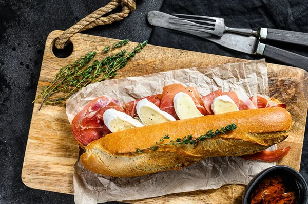 Jambonlu sandviç, dilimleme tahtasındaki peynirli peynirli sandviç. Siyah arkaplan, üst görünüm.