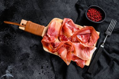 İspanyol jamonu Serrano, jambon. Siyah arkaplan, üst görünüm, metin için boşluk