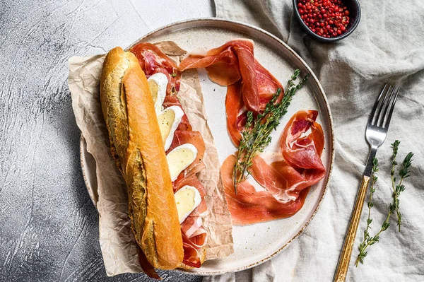 Jamon jambonlu sandviç, paleta iberica, kesim tahtasında Camembert peyniri. Gri arkaplan, üst görünüm.