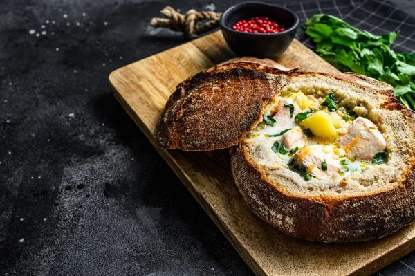 Finnish Creamy fish soup with salmon, trout, potatoes served in bread. Black background, top view, space for text — Stock Image Finnish Creamy fish soup with salmon, trout, potatoes served in bread. Black background, top view, space for text Royalty Free Stock Images