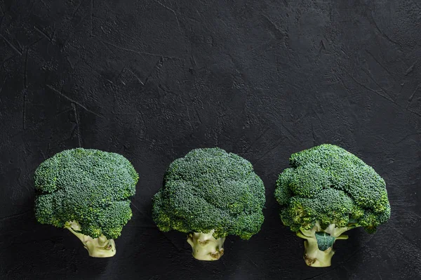 Roher grüner Brokkoli auf schwarzem Hintergrund. Ansicht von oben — Stockfoto