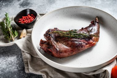 Pişmiş tavşan bacağı ve bitkiler, tekstil peçetesinde servis ediliyor. Organik et. Üst görünüm.