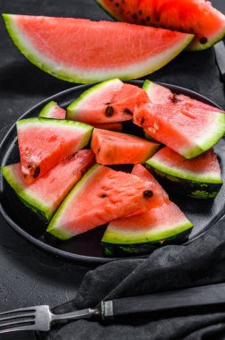 Olgun karpuz dilimleri koyu arkaplanda bir tabakta. Seçici odak.