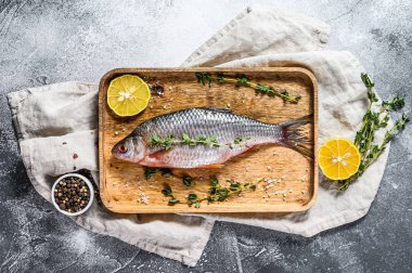 Tahta tepside sazan balığı. Nehir organik balığı. Gri arka plan. Üst görünüm