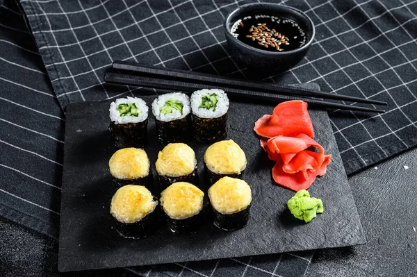 Siyah taşla servis edilen çeşitli suşiler. Siyah arka plan. Üst görünüm