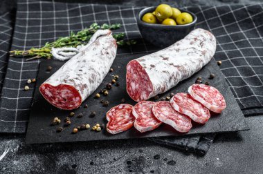 Fuet Salam dilimleri ve Rosemary. Geleneksel İspanyol sosisi. Siyah arka plan. Üst görünüm